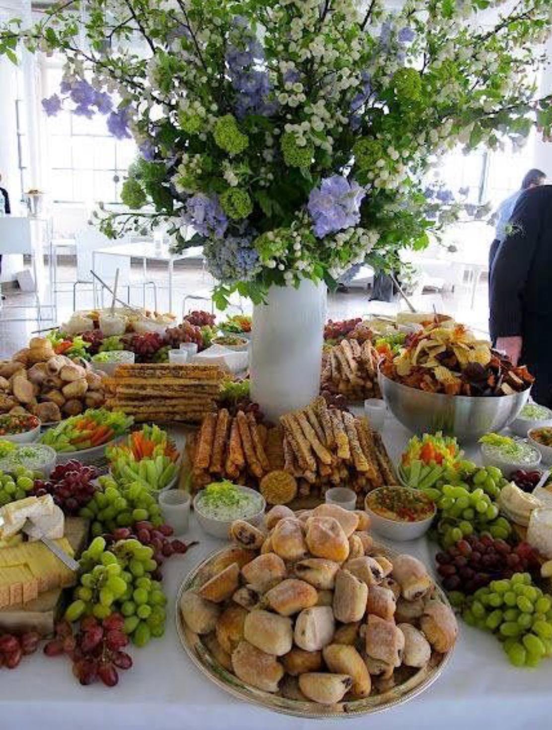 Catering grazing table with fresh fruit, cheese and flowers